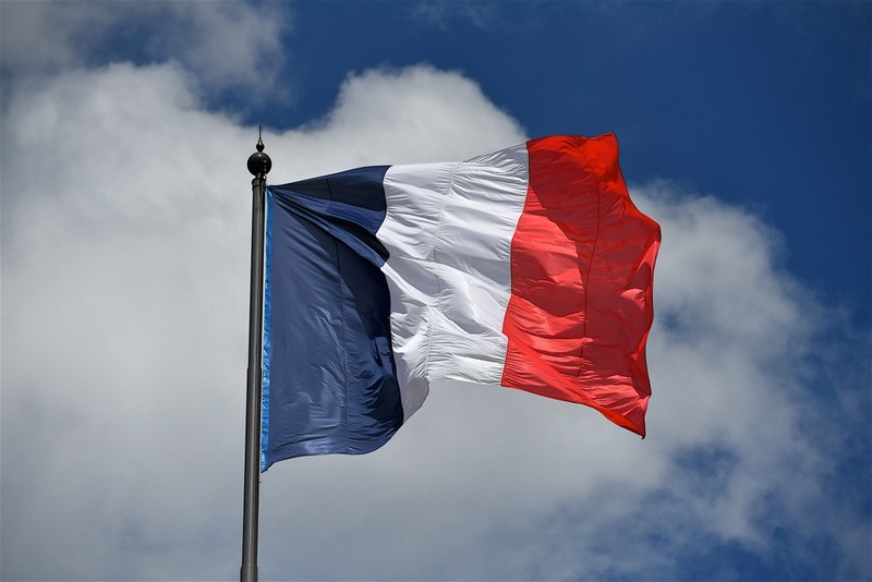 French Flag on Pole Against Blue Cloudy Sky